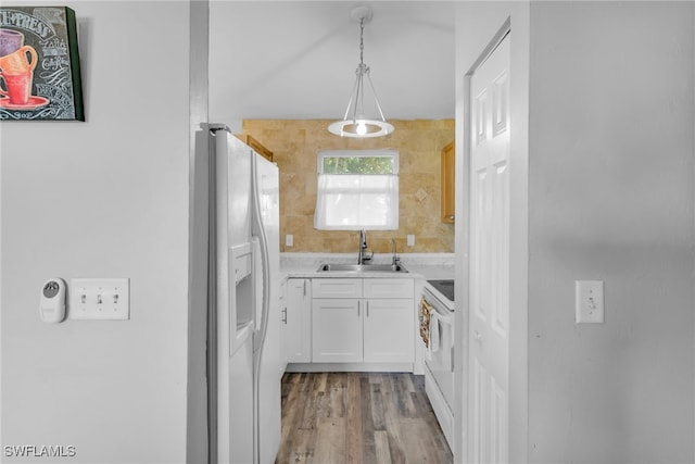 kitchen with sink, white appliances, light hardwood / wood-style flooring, hanging light fixtures, and white cabinets