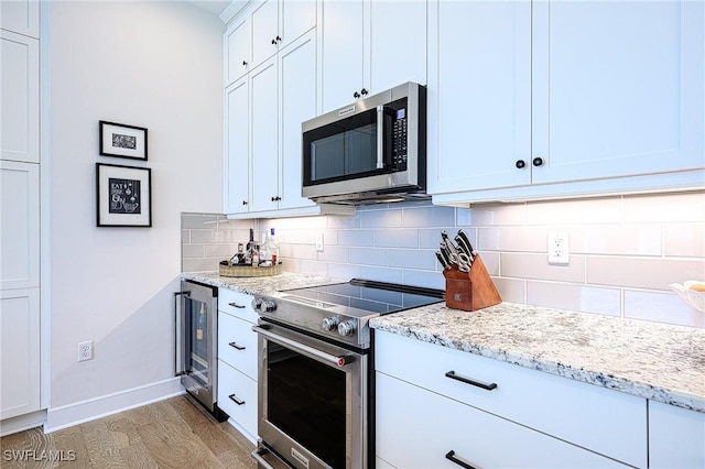 kitchen with white cabinets, beverage cooler, decorative backsplash, stainless steel appliances, and light stone countertops