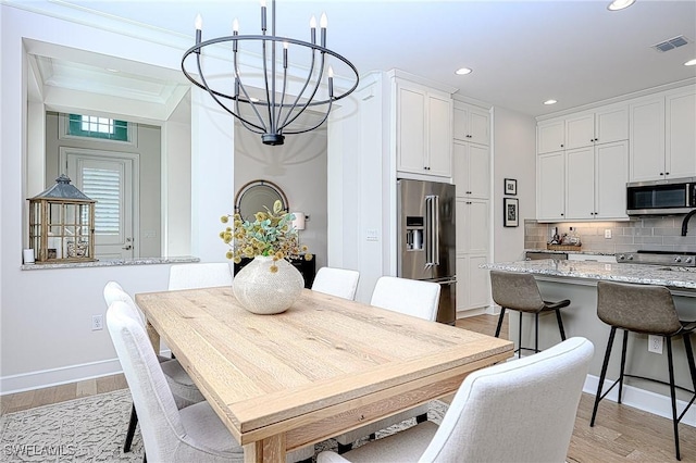 dining space with crown molding, a chandelier, and light wood-type flooring