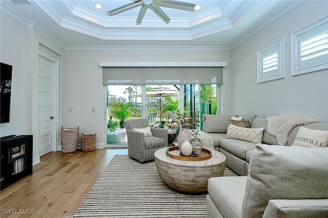 living room featuring crown molding, ceiling fan, a towering ceiling, light hardwood / wood-style floors, and a raised ceiling