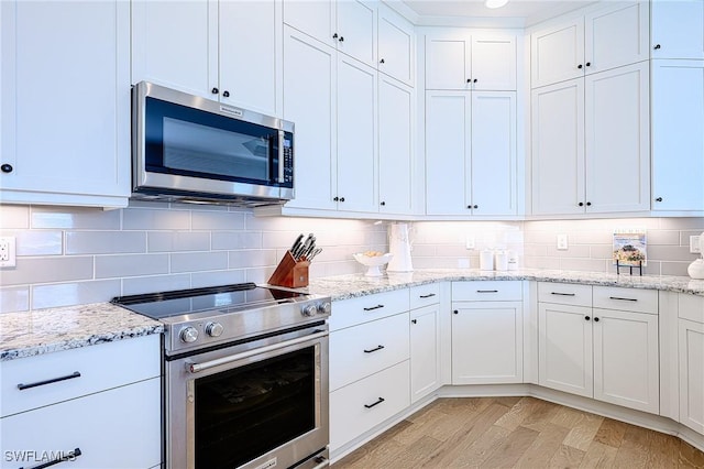 kitchen featuring tasteful backsplash, appliances with stainless steel finishes, light stone countertops, and white cabinets