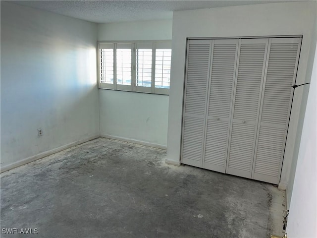 unfurnished bedroom with a closet, concrete flooring, and a textured ceiling