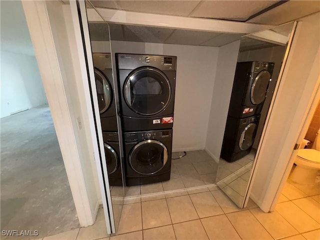 laundry area with light tile patterned floors and stacked washer and clothes dryer