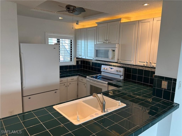 kitchen with sink, white cabinetry, tile counters, white appliances, and backsplash