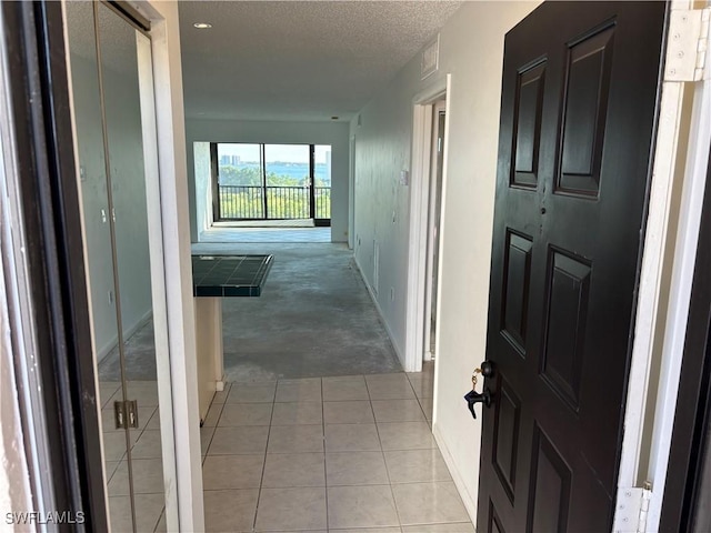 corridor featuring light tile patterned floors and a textured ceiling