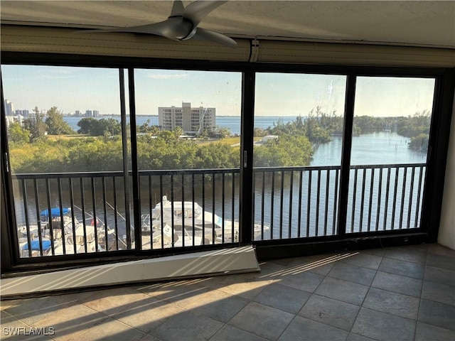 unfurnished sunroom featuring ceiling fan and a water view