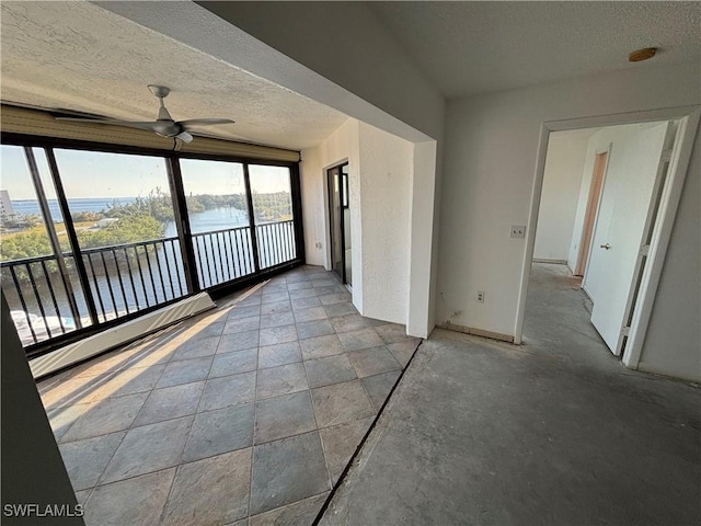 interior space featuring ceiling fan, a water view, and a textured ceiling