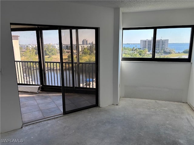 empty room featuring a water view, concrete flooring, and a textured ceiling