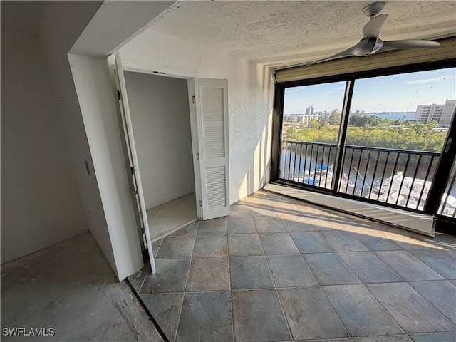 interior space with ceiling fan, a textured ceiling, and a water view