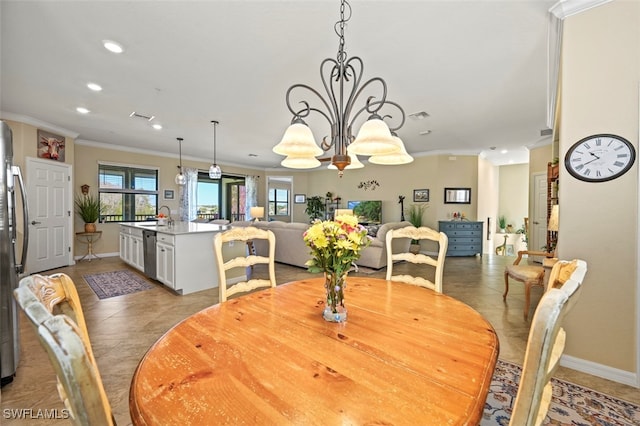 dining area featuring ornamental molding, sink, a notable chandelier, and a healthy amount of sunlight