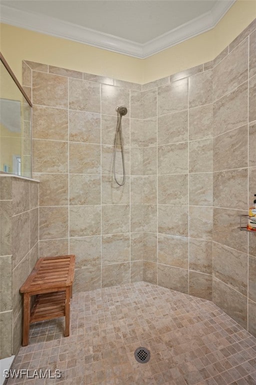 bathroom featuring crown molding and a tile shower