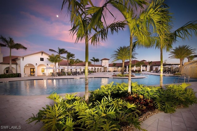 pool at dusk featuring a patio