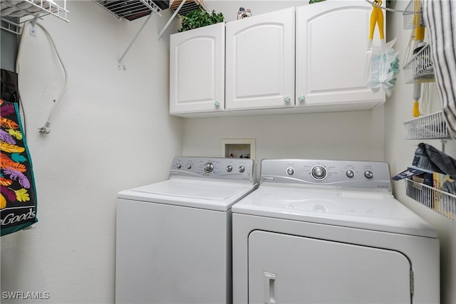 clothes washing area featuring cabinets and washer and dryer