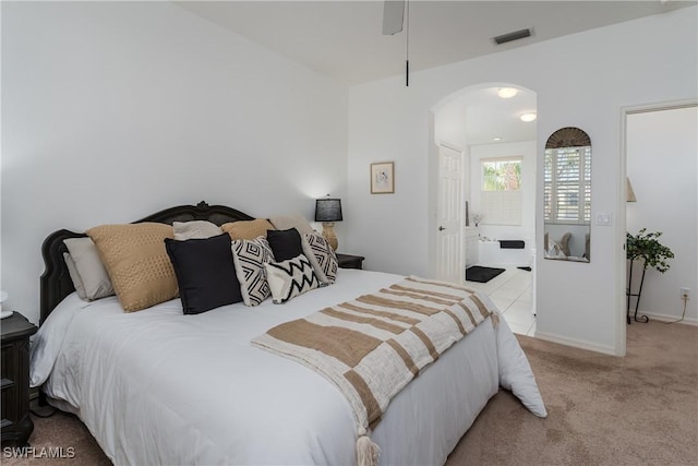 bedroom with connected bathroom and light carpet