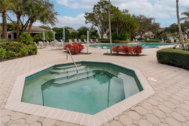 view of swimming pool with a hot tub and a patio area