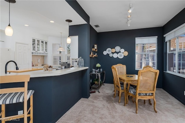 kitchen featuring pendant lighting, track lighting, kitchen peninsula, and light carpet