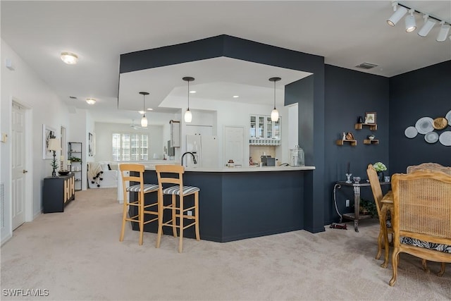 kitchen with pendant lighting, a kitchen bar, white fridge with ice dispenser, kitchen peninsula, and light carpet