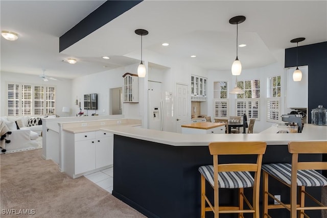 kitchen featuring white cabinetry, light carpet, hanging light fixtures, kitchen peninsula, and white fridge with ice dispenser