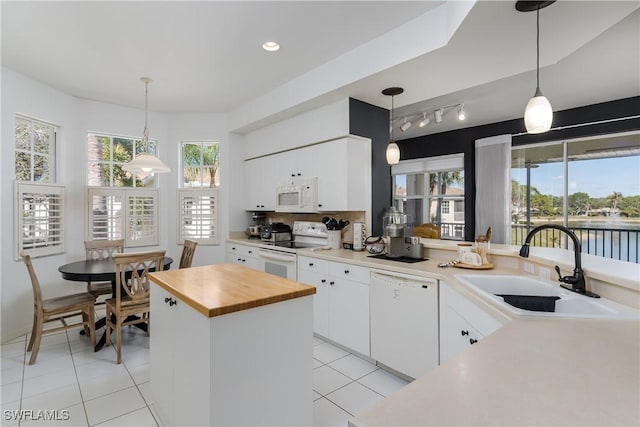 kitchen with sink, white appliances, a center island, a water view, and white cabinets