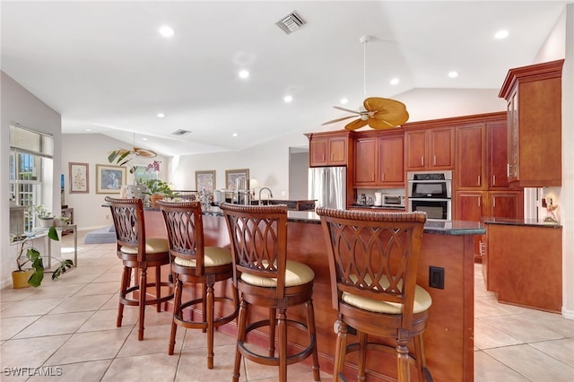 kitchen with lofted ceiling, appliances with stainless steel finishes, a kitchen breakfast bar, and a center island