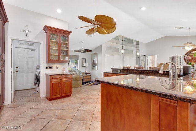 kitchen with ceiling fan, lofted ceiling, light tile patterned floors, and dark stone countertops