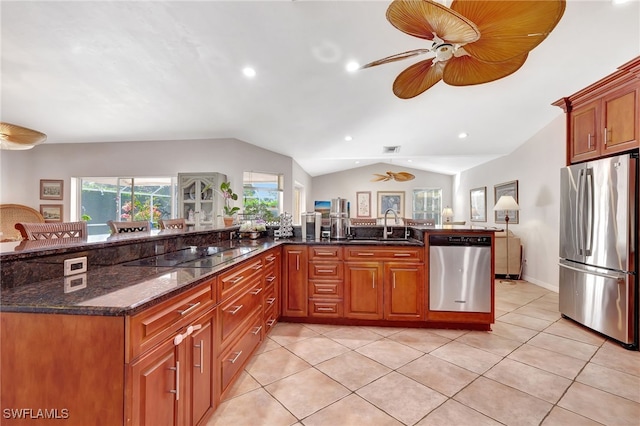 kitchen with light tile patterned flooring, lofted ceiling, sink, dark stone counters, and stainless steel appliances