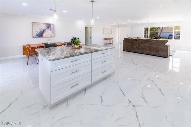 kitchen featuring light stone counters, crown molding, decorative light fixtures, a center island, and white cabinets