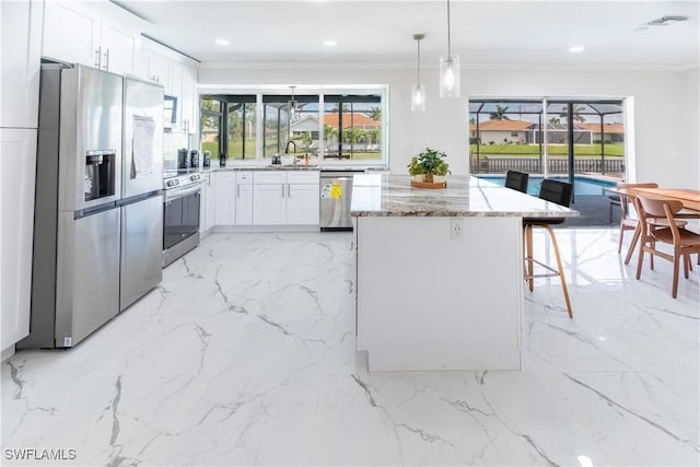 kitchen with crown molding, hanging light fixtures, appliances with stainless steel finishes, light stone countertops, and white cabinets