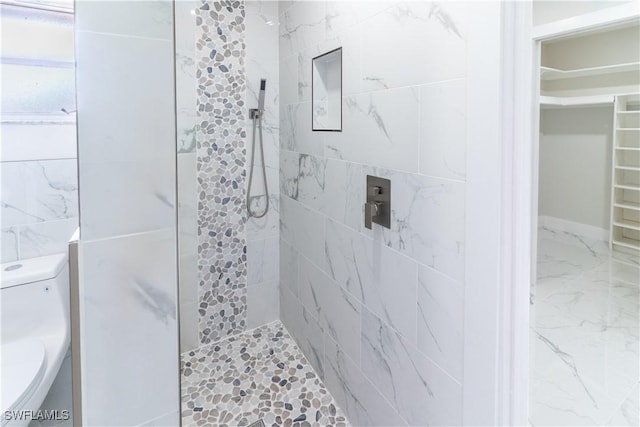 bathroom with tiled shower and toilet