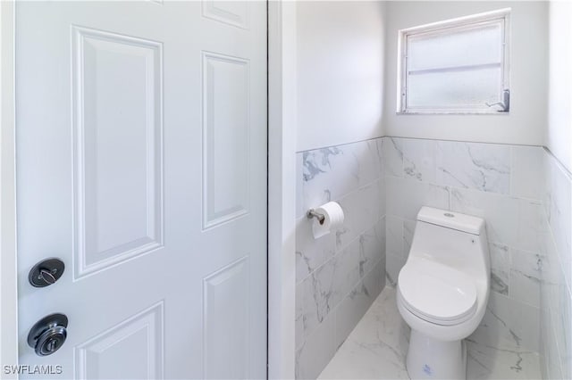 bathroom featuring tile walls and toilet