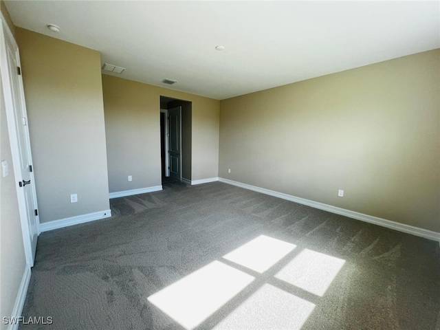 spare room with dark carpet