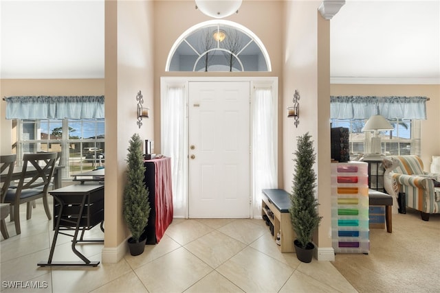 foyer featuring crown molding, a towering ceiling, and light tile patterned floors