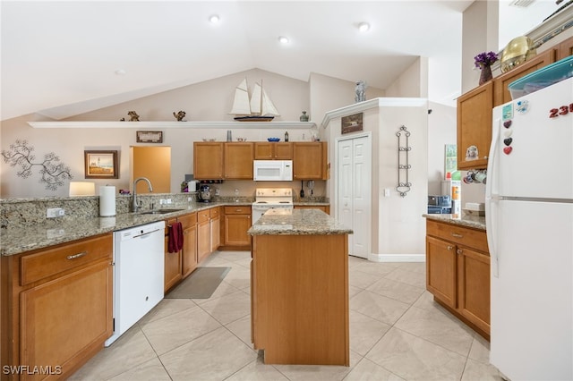 kitchen featuring sink, light stone counters, a center island, kitchen peninsula, and white appliances