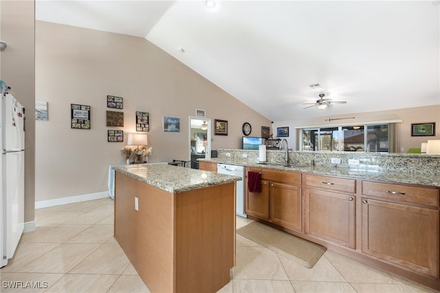 kitchen featuring light stone counters, white appliances, sink, and a kitchen island