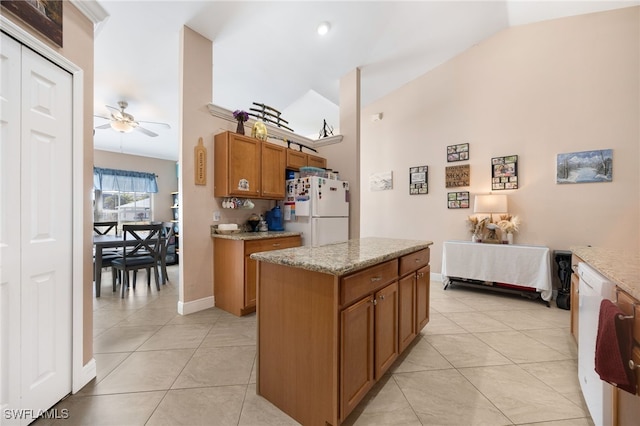 kitchen with white appliances, ceiling fan, a kitchen island, light tile patterned flooring, and vaulted ceiling