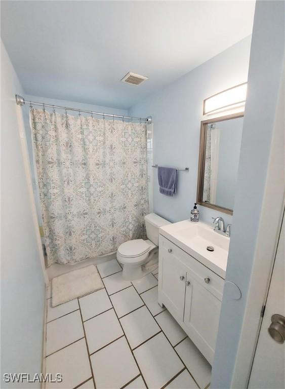 bathroom with a shower with curtain, vanity, tile patterned floors, and toilet