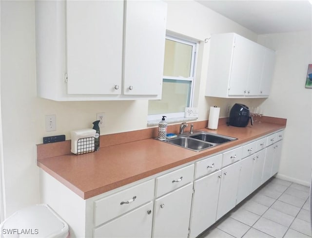 kitchen featuring light tile patterned flooring, sink, and white cabinets