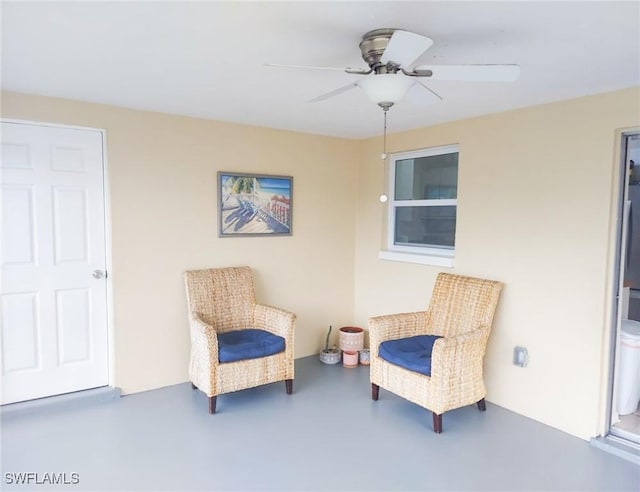 sitting room featuring ceiling fan and concrete floors