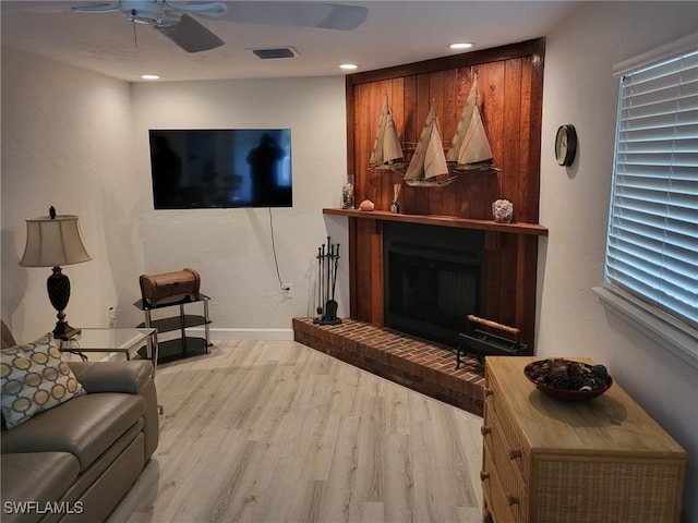 living room with ceiling fan, a fireplace, and light hardwood / wood-style flooring