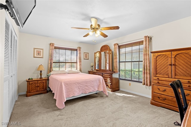 carpeted bedroom with multiple windows, ceiling fan, and a closet