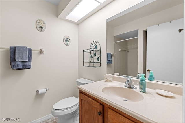 bathroom featuring vanity, a skylight, toilet, and a tile shower