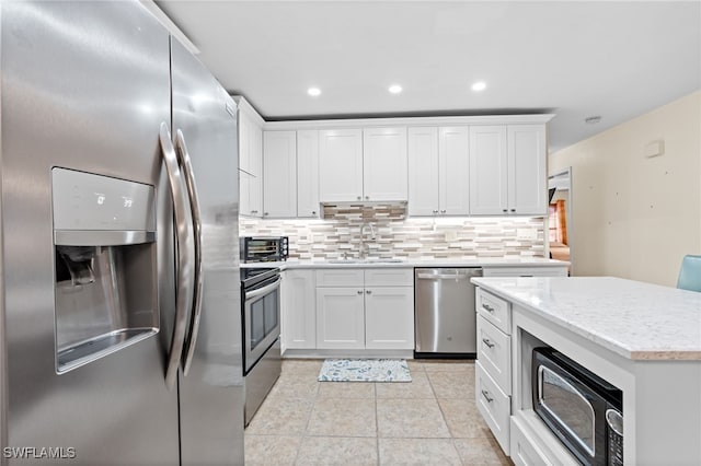 kitchen featuring white cabinetry, stainless steel appliances, sink, and backsplash