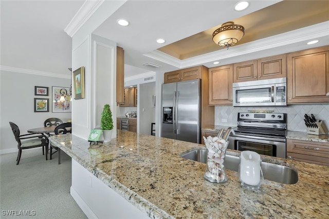 kitchen featuring stainless steel appliances, tasteful backsplash, light stone countertops, ornamental molding, and light carpet