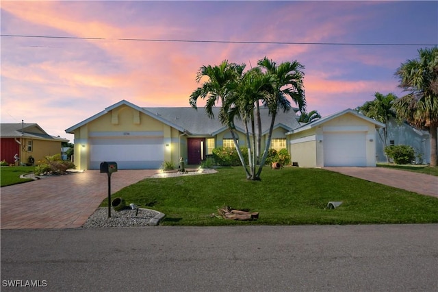 single story home featuring a garage and a yard