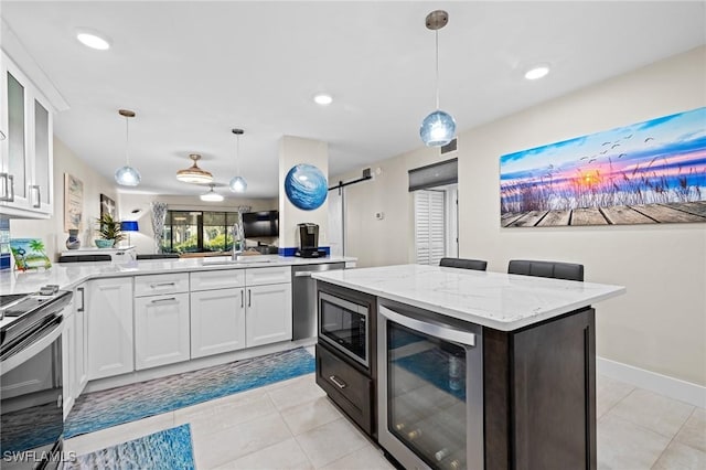 kitchen featuring appliances with stainless steel finishes, white cabinets, wine cooler, hanging light fixtures, and a barn door