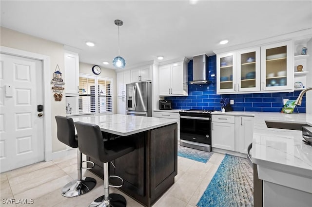 kitchen featuring wall chimney range hood, stainless steel appliances, sink, and light stone countertops