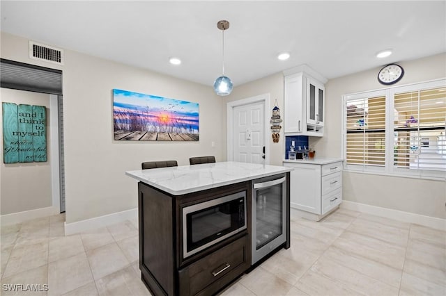 kitchen with white cabinetry, beverage cooler, hanging light fixtures, and built in microwave