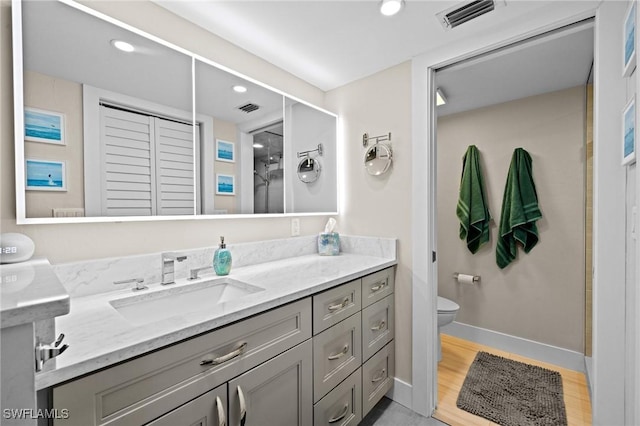 bathroom with hardwood / wood-style flooring, vanity, a shower, and toilet