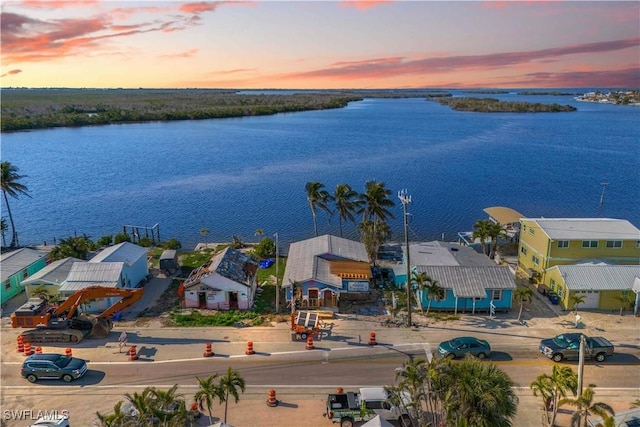 aerial view at dusk featuring a water view