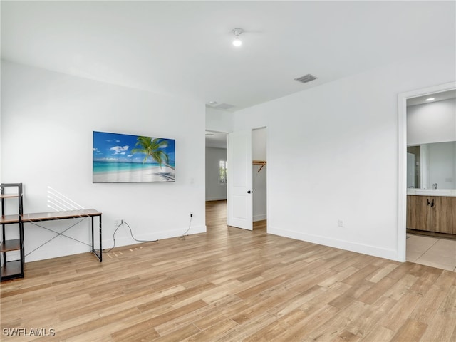 unfurnished living room with light wood-type flooring, baseboards, and visible vents